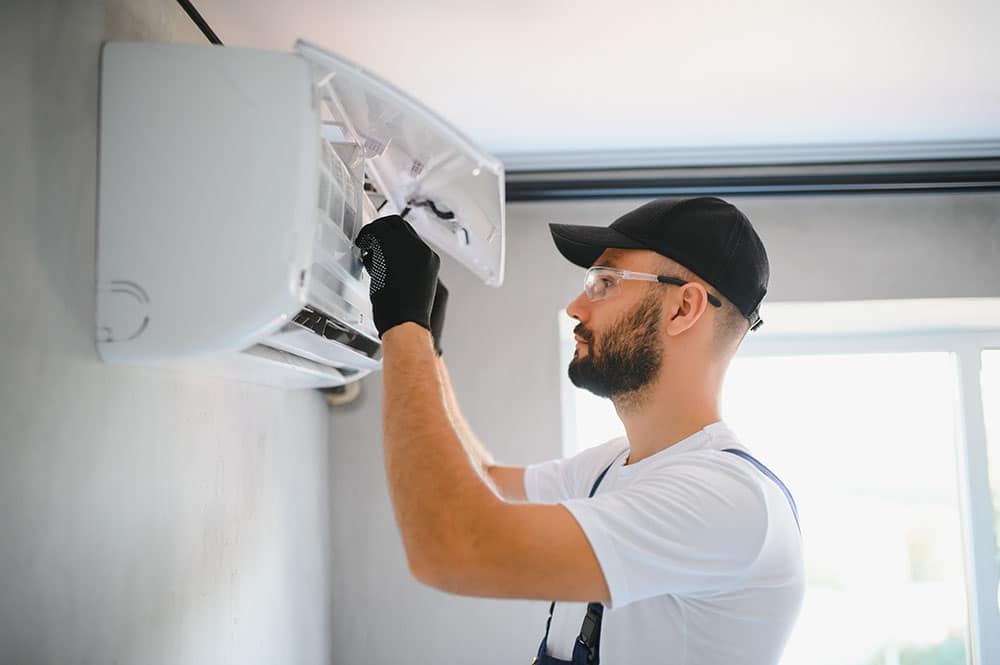 A technician servicing a modern heating unit, with tools in hand and a focused expression.