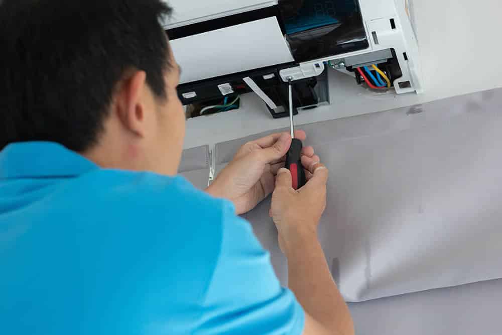 A technician performing a detailed inspection of a central AC unit, with tools and equipment neatly organized nearby.