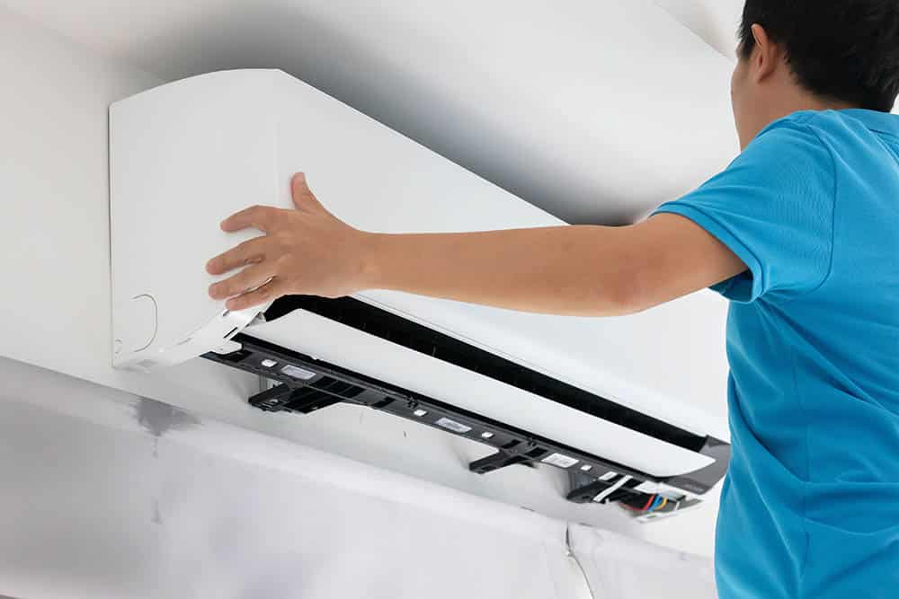 A modern central AC unit being installed by a technician, with a focus on the installation process and tools.