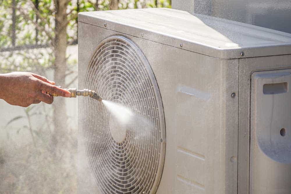 Technician cleaning AC coils with brush and gloves on