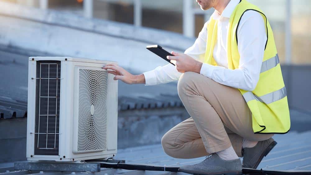 Technician replacing AC compressor on rooftop unit