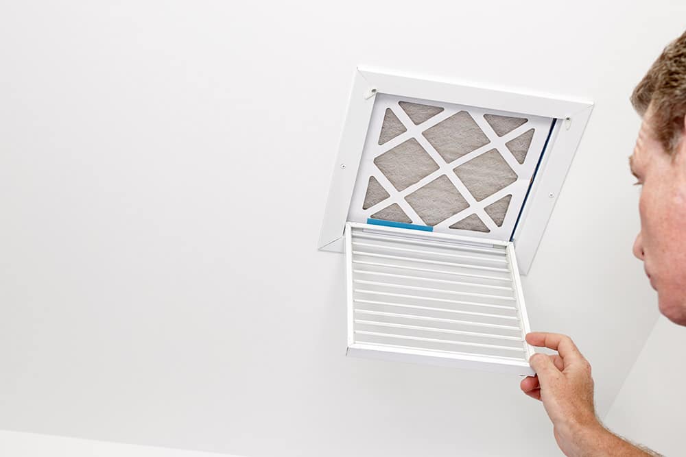 Technician inserting vacuum hose into ceiling air vent