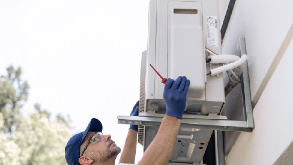 Technician installing AC unit on exterior wall of house