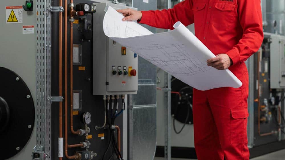 Technician reviewing blueprints beside HVAC equipment and tools