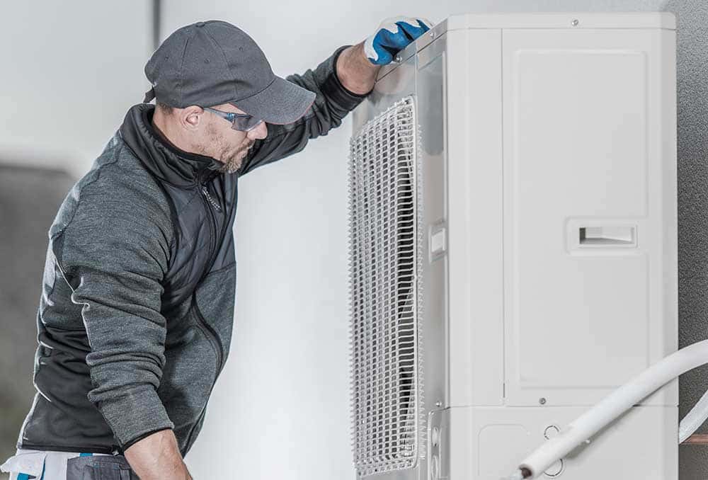 an air conditioning technician leveling an outdoor unit