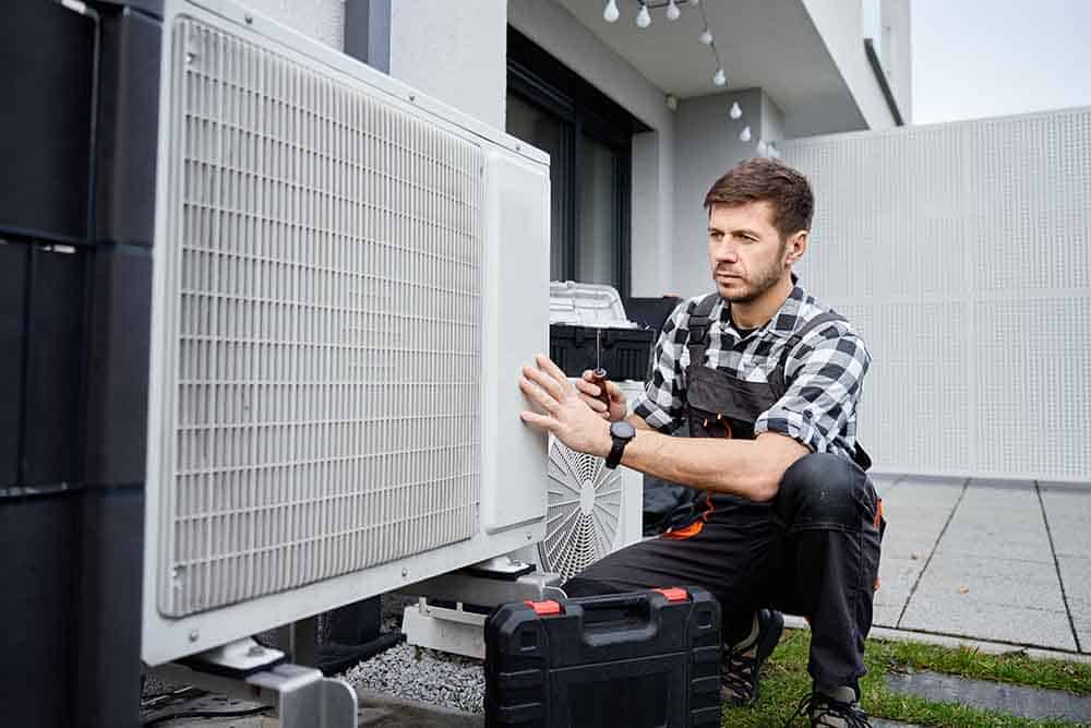 an hvac technician cleaning a metal outdoor unit