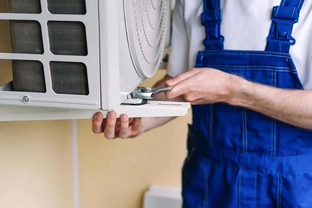 An HVAC technician installing an outdoor air conditioner unit