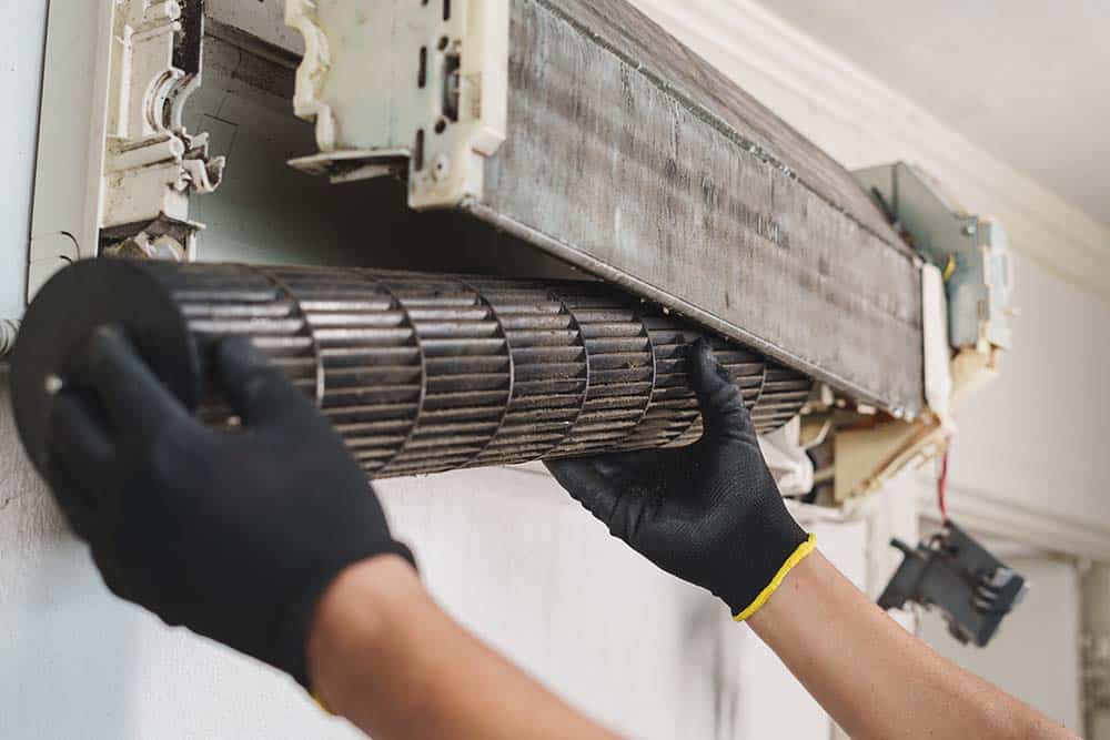 An air conditioning technician replacing a dirty filter