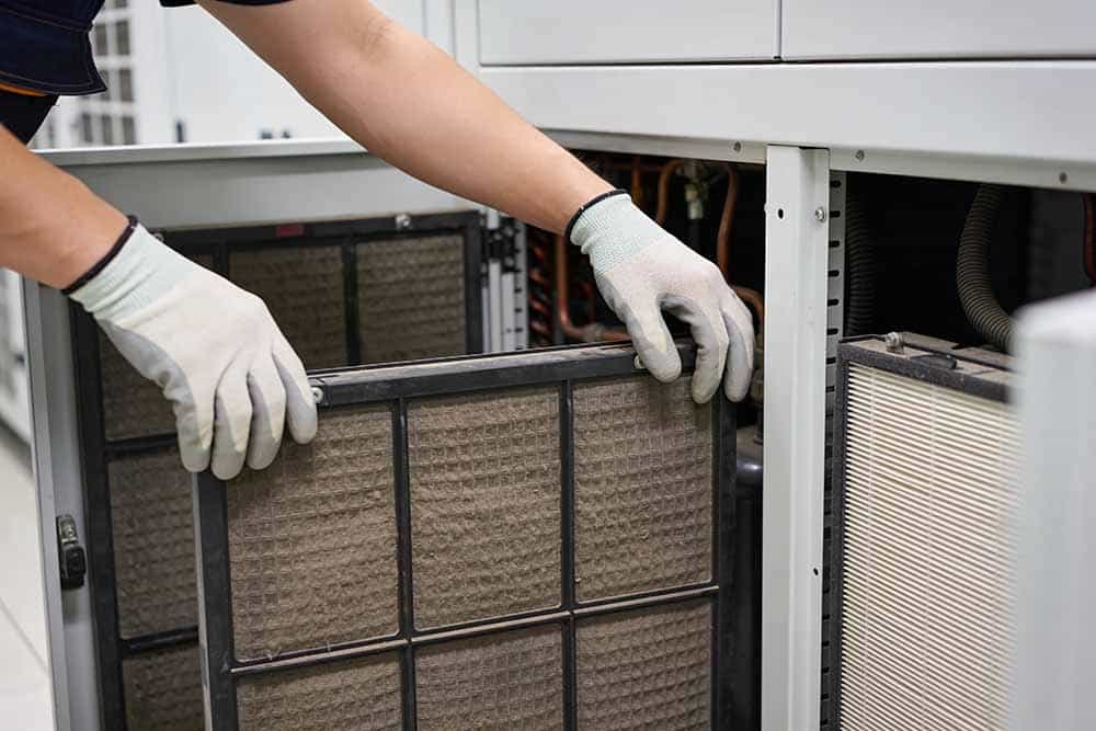 An air conditioning technician replacing a dirty filter