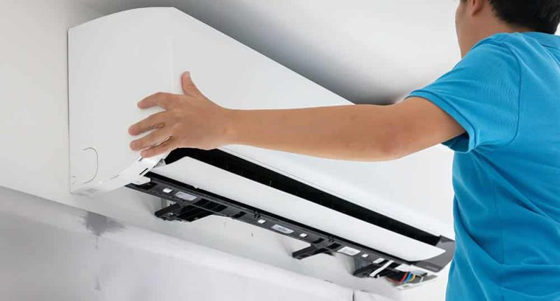 A modern central AC unit being installed by a technician, with a focus on the installation process and tools.