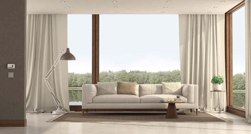 A bright, airy living room with open windows, healthy green houseplants, and sunlight filtering through sheer curtains. A family relaxes comfortably, hinting at fresh indoor air without visible appliances.